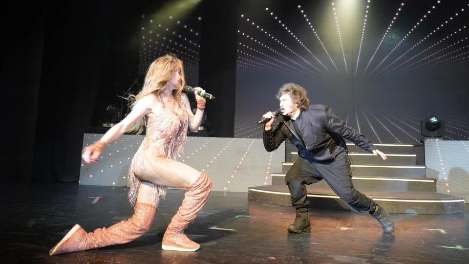 Javier Milei en el escenario junto a Fátima Flórez cantando “El rock del gato” durante un evento en Mar del Plata con público presente.