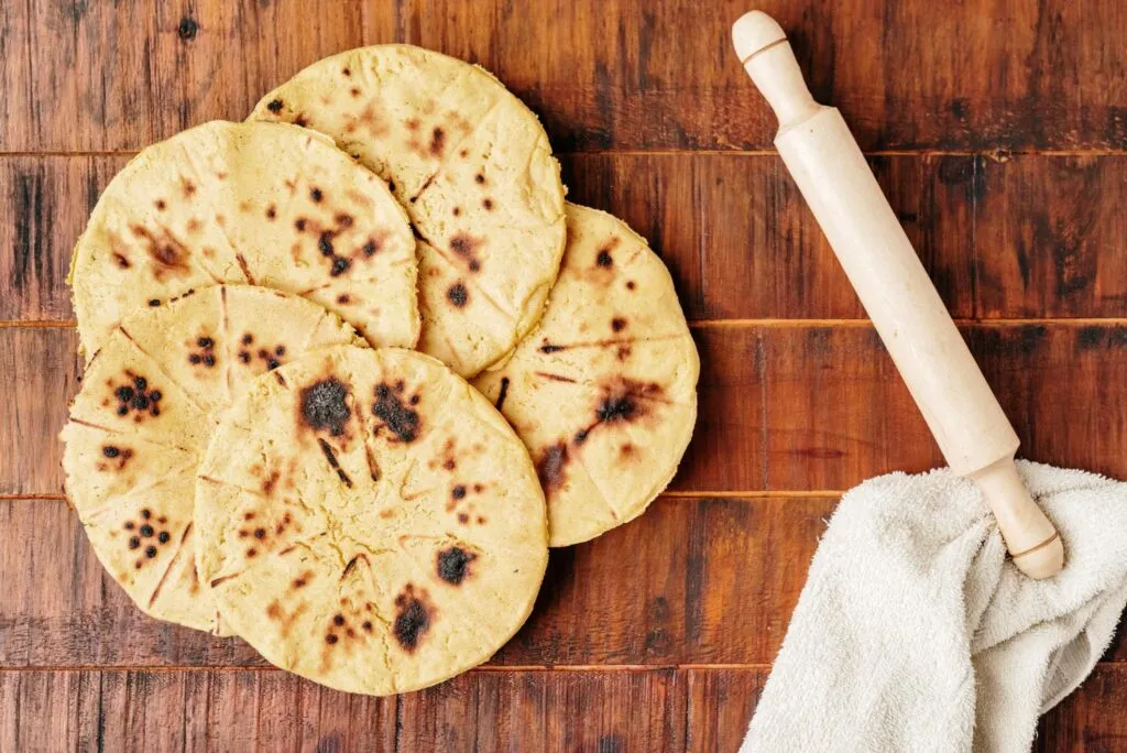 Arepa símbolo de orgullo en Colombia servida con queso y acompañamientos tradicionales en mesa familiar.