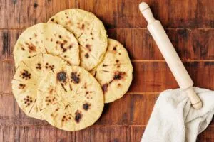 Arepa símbolo de orgullo en Colombia servida con queso y acompañamientos tradicionales en mesa familiar.