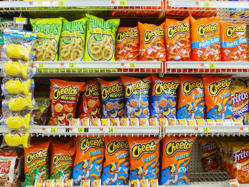 Doritos, Cheetos, Pringles y papas fritas en supermercado representando snacks más consumidos en América Latina