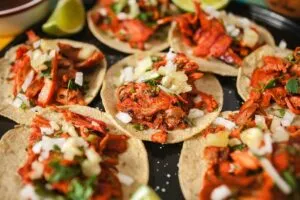 Tacos al pastor recién cortados del trompo con piña y cilantro representando la gastronomía mexicana en Estados Unidos