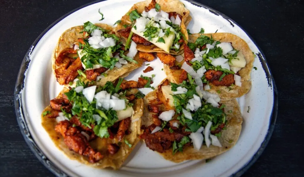 Una mesa colorida con tacos, arepas, empanadas y otros platillos tradicionales latinoamericanos.