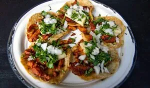 Una mesa colorida con tacos, arepas, empanadas y otros platillos tradicionales latinoamericanos.
