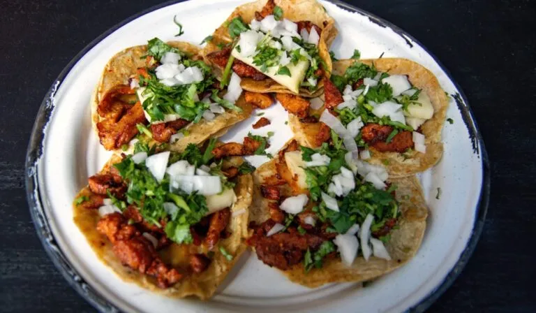 Una mesa colorida con tacos, arepas, empanadas y otros platillos tradicionales latinoamericanos.