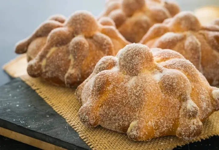 Pan de muerto tradicional colocado junto a elementos de una ofrenda mexicana